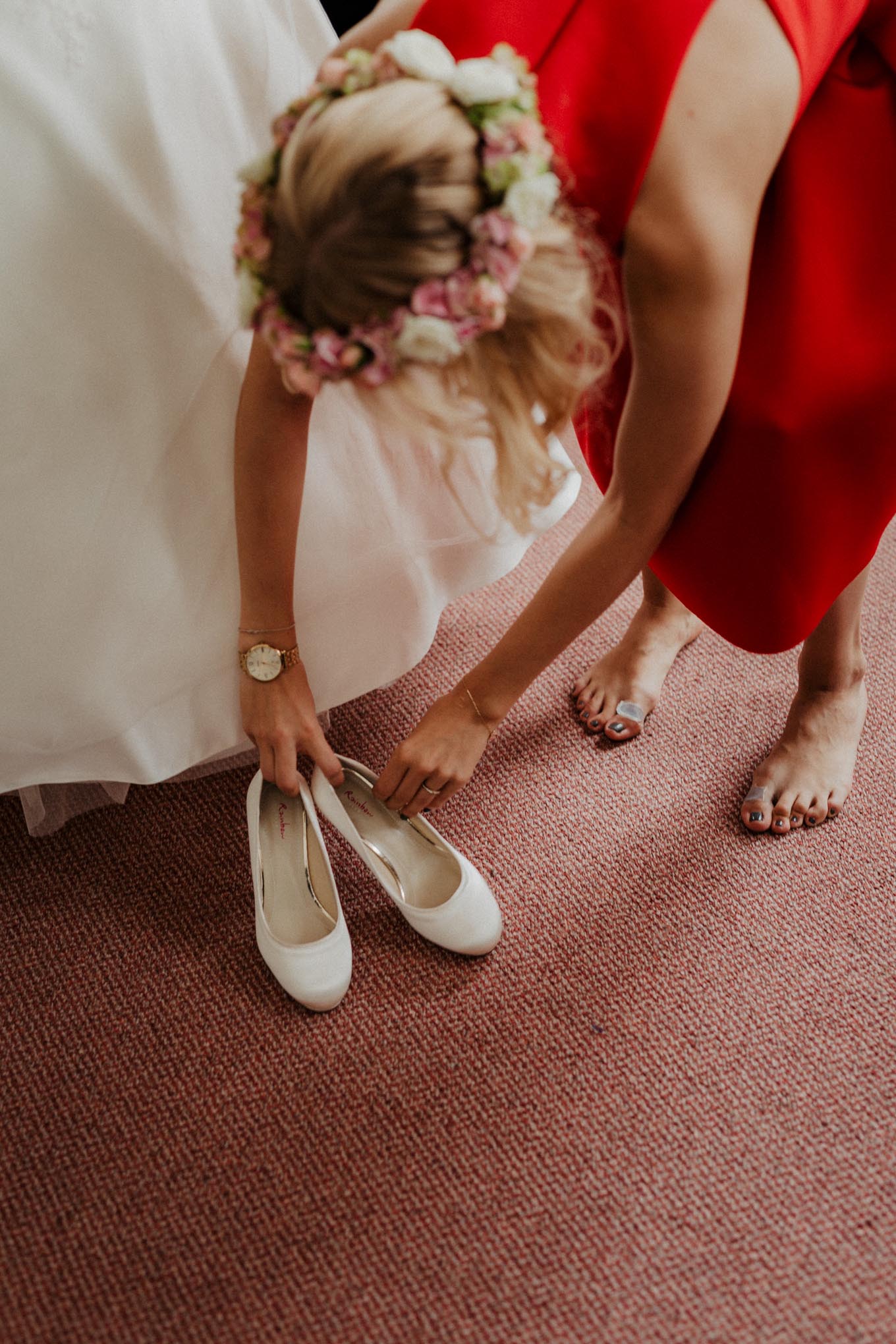 Trauzeugin hilft Braut in ihre Schuhe