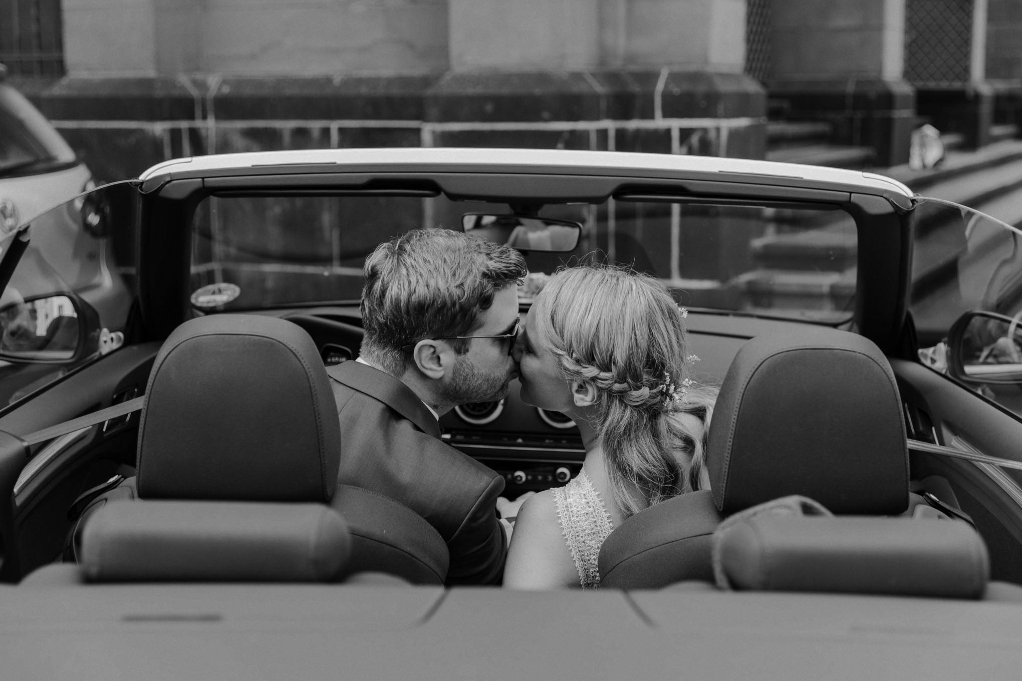Küssendes Brautpaar im Auto